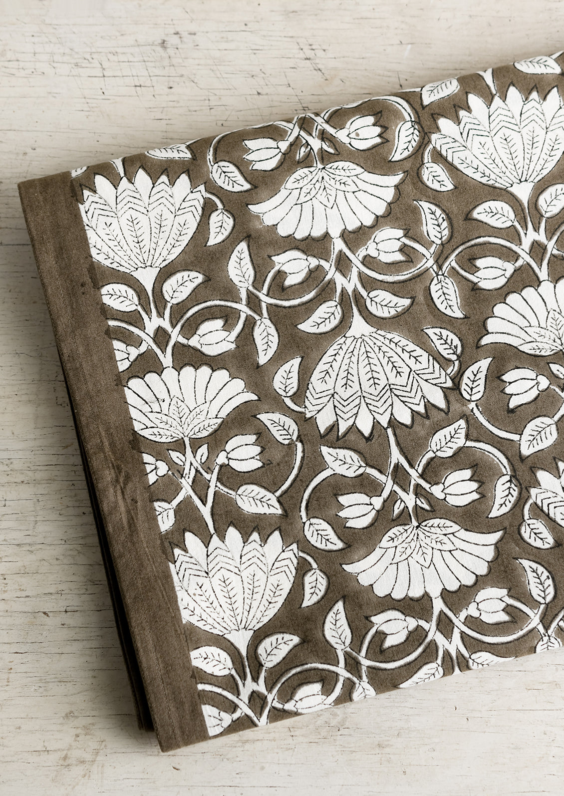 A block printed tablecloth with white lotus print on brown background.