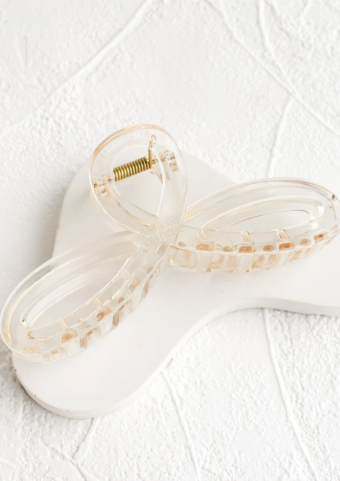 A curvy hair clip with knotted loop design in shiny transparent pale brown.