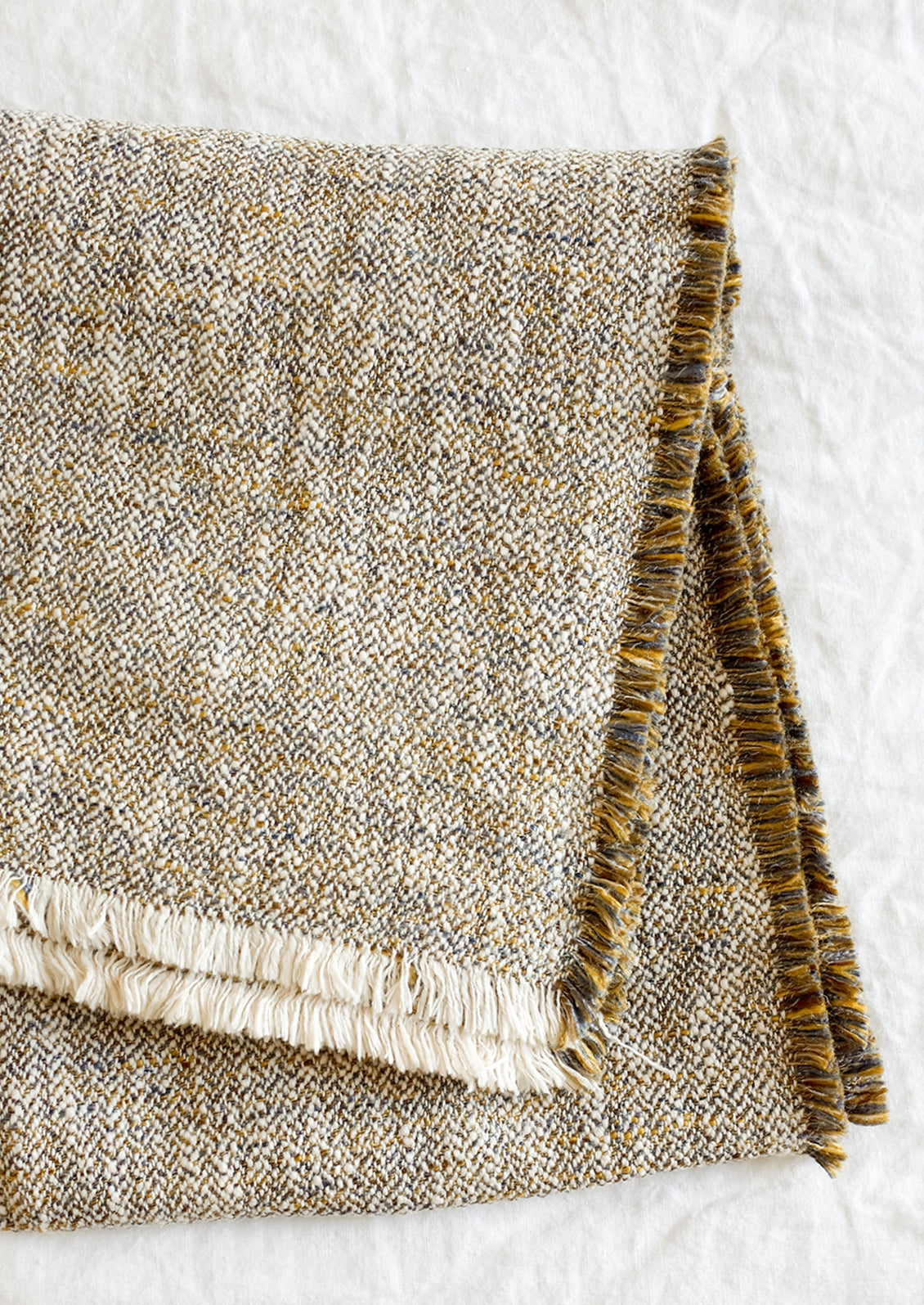 A textured throw in woven blue-ochre color.