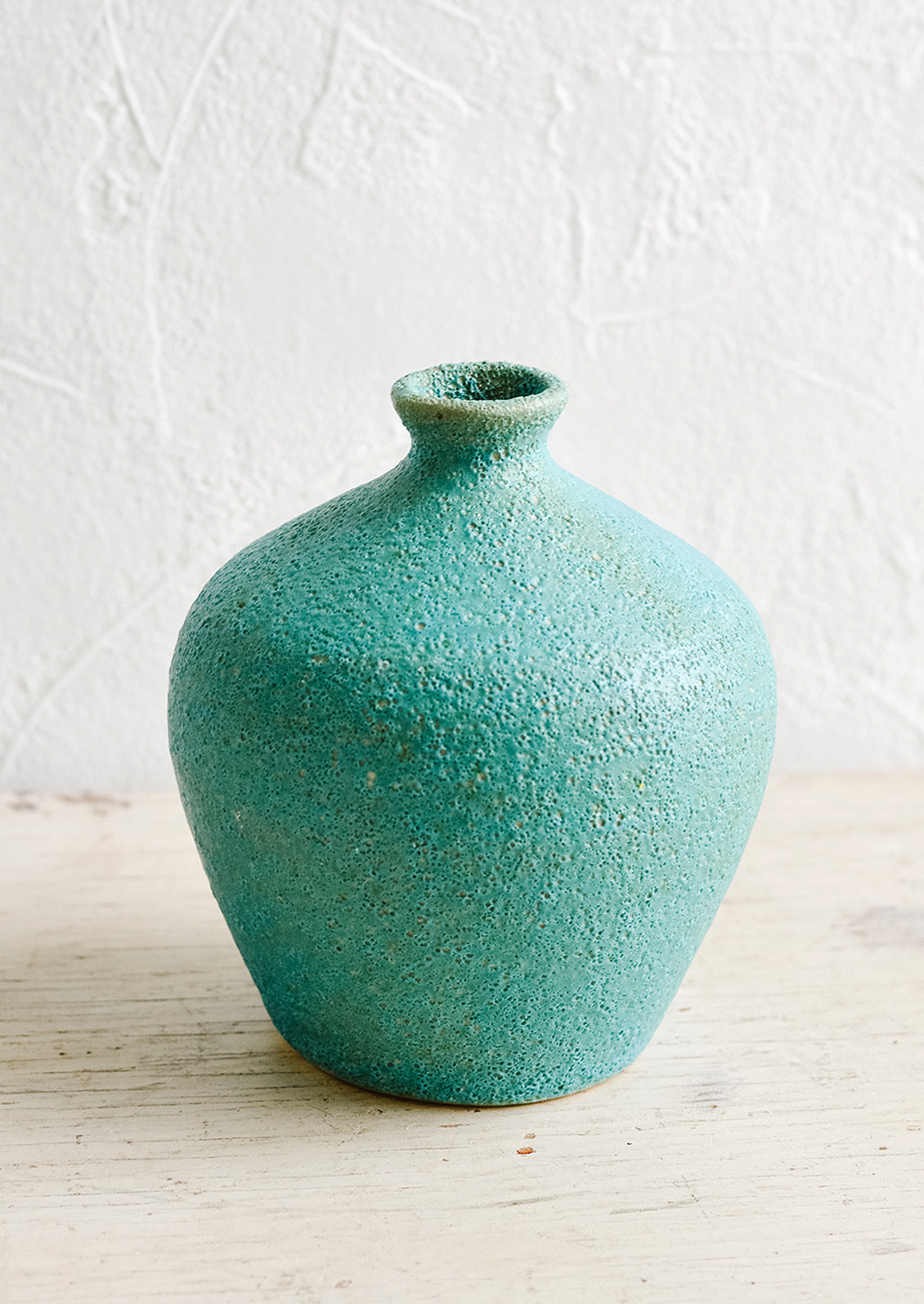 A textured turquoise ceramic bud vase with tapered top.