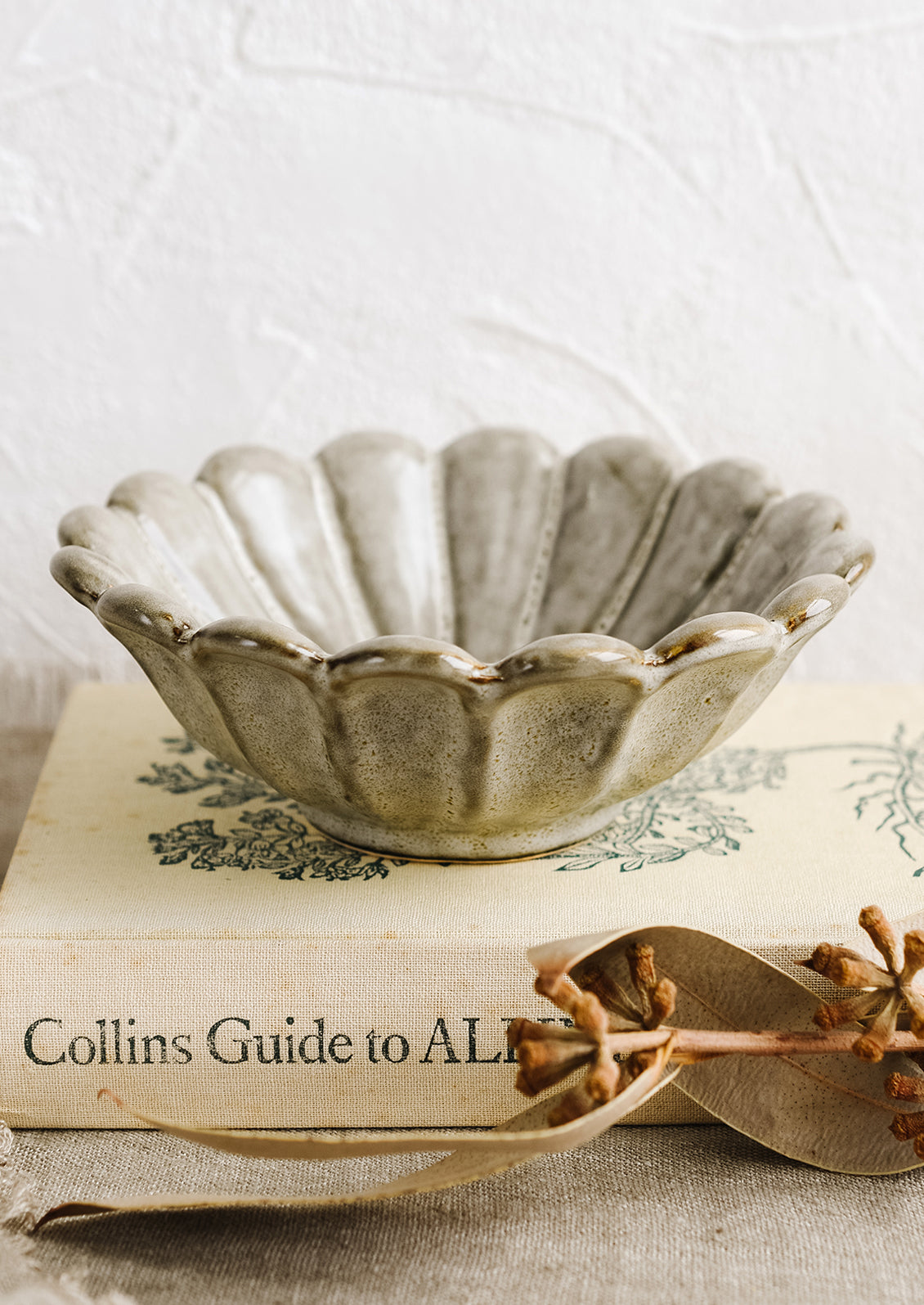 A grey flower shaped bowl styled on top a book.