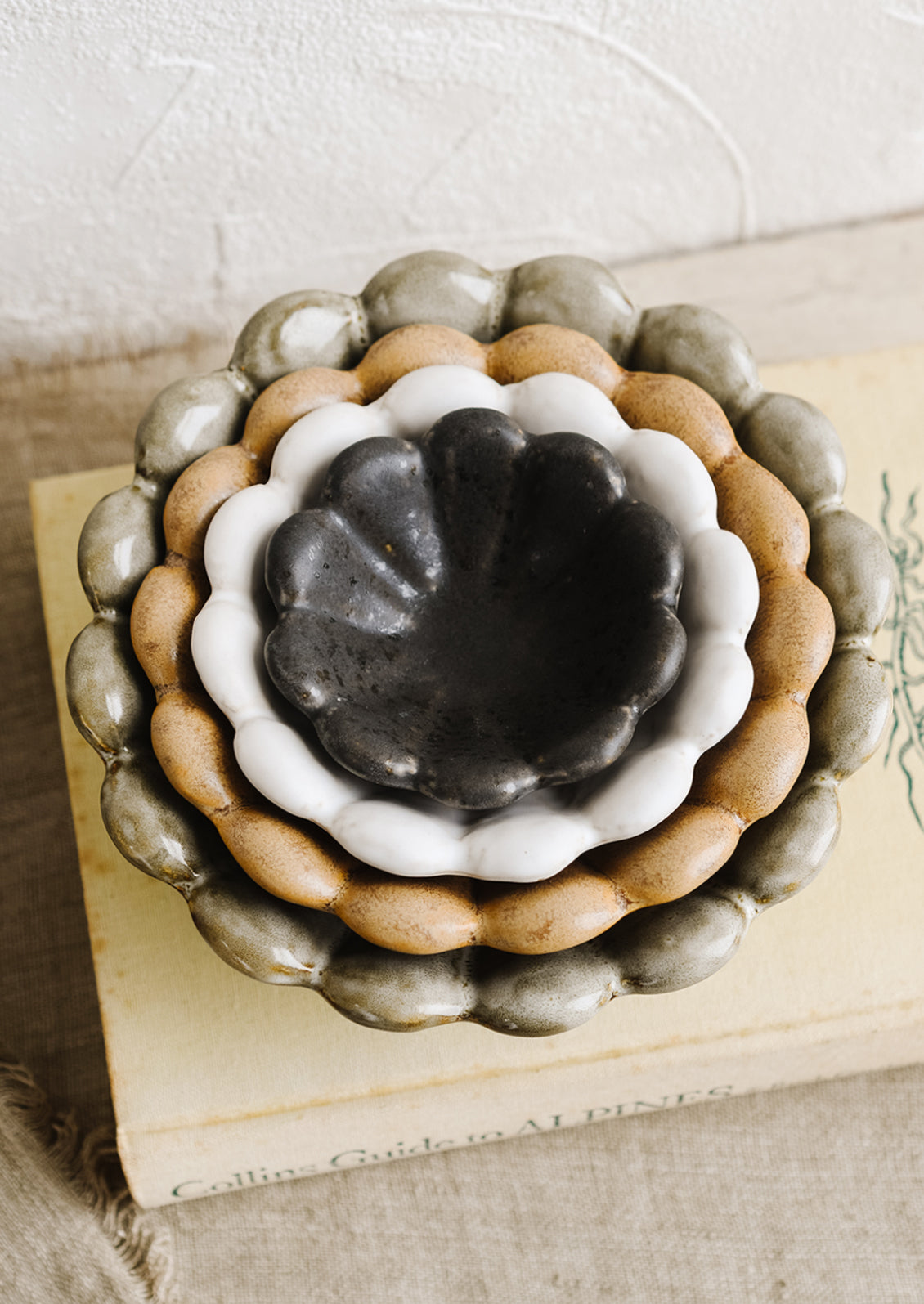 Nesting flower shaped ceramic bowls in different colors.
