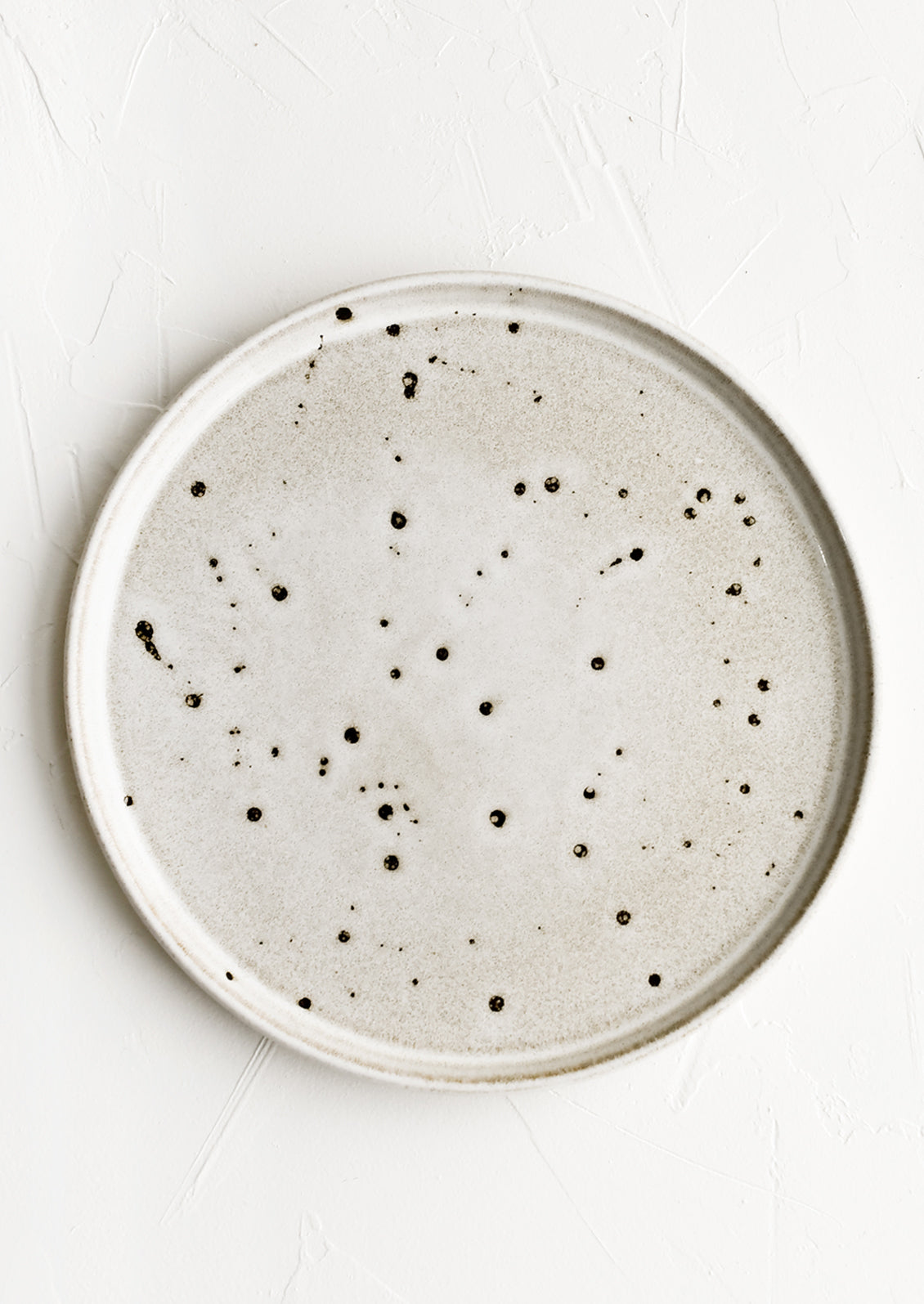 A ceramic plate with grey-tan speckled glaze.