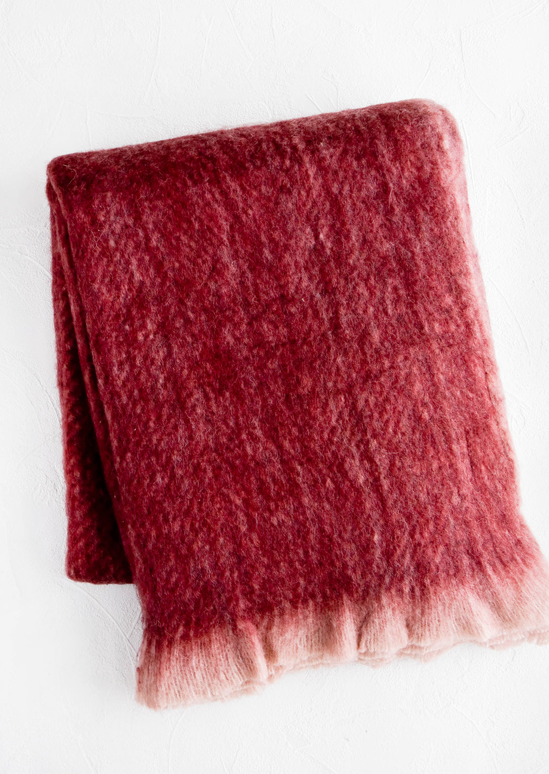 Fuzzy, mohair-like throw blanket in wine red with faded fringe trim