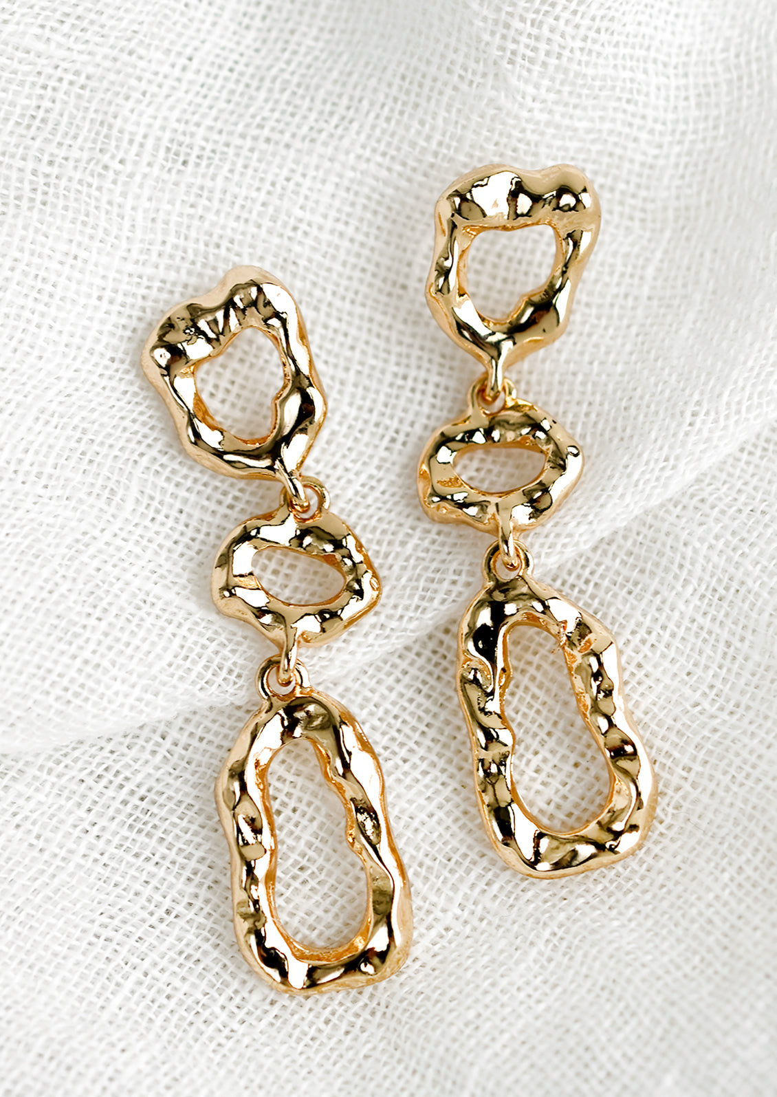 A pair of gold abstract shape drop earrings with melted metal look.