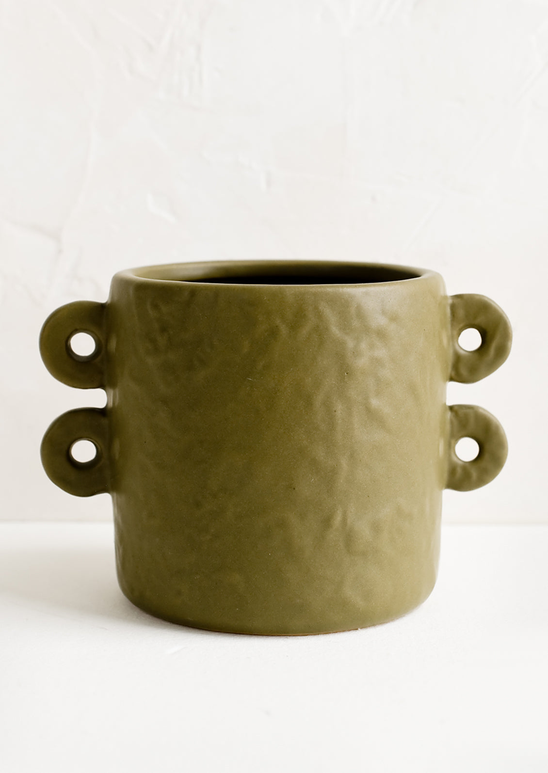 An army green round planter with decorative loop handles at sides.