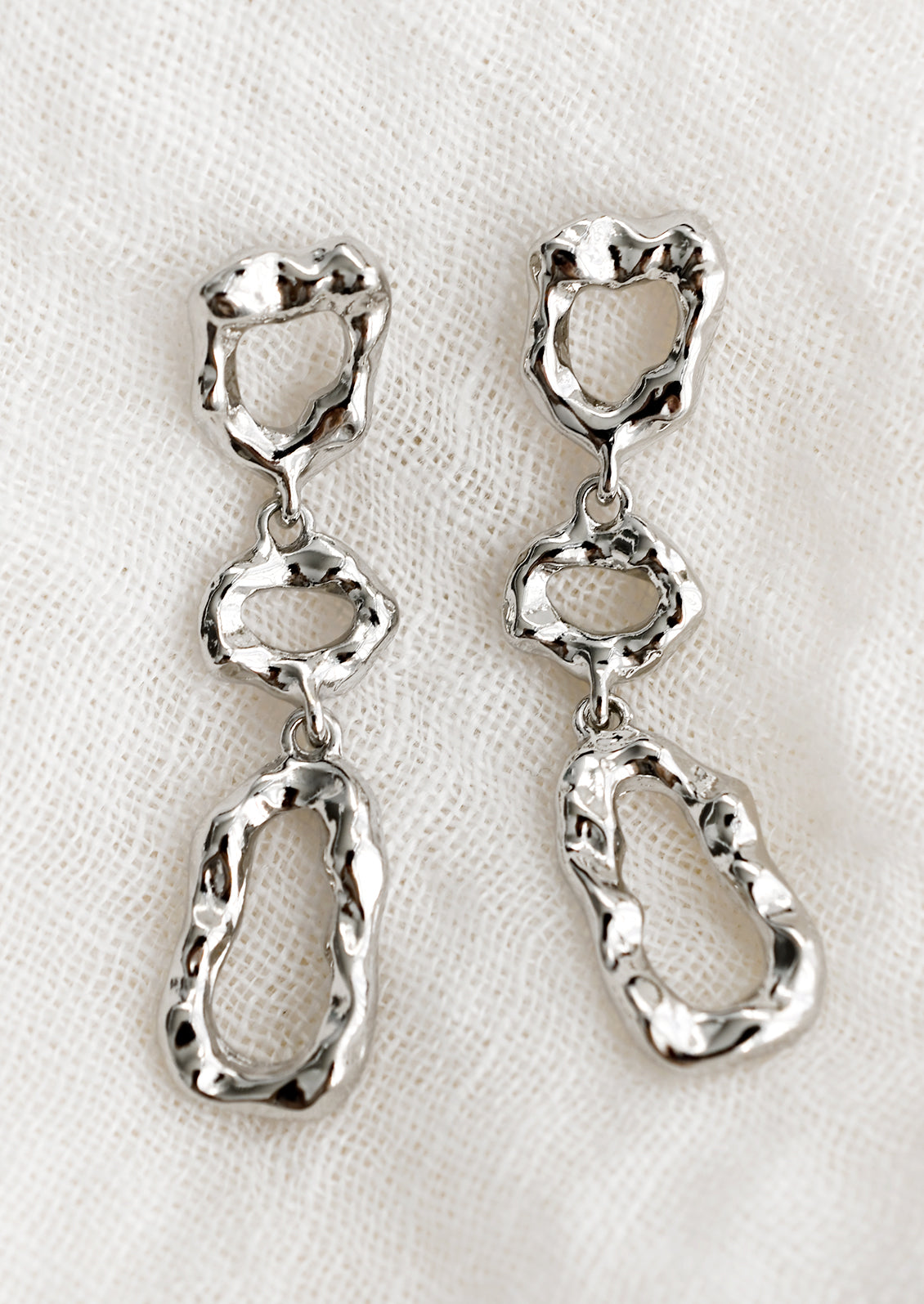 A pair of silver abstract shape drop earrings with melted metal look.