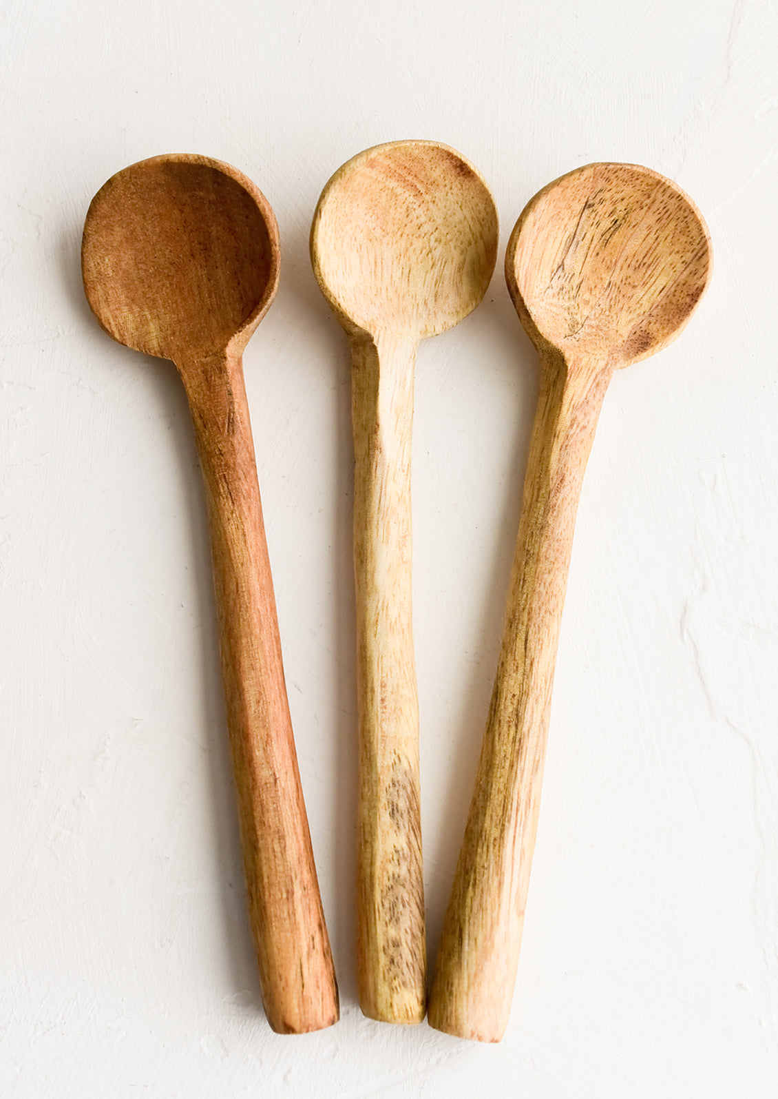 Three carved wooden teaspoons in slightly different wood colors.