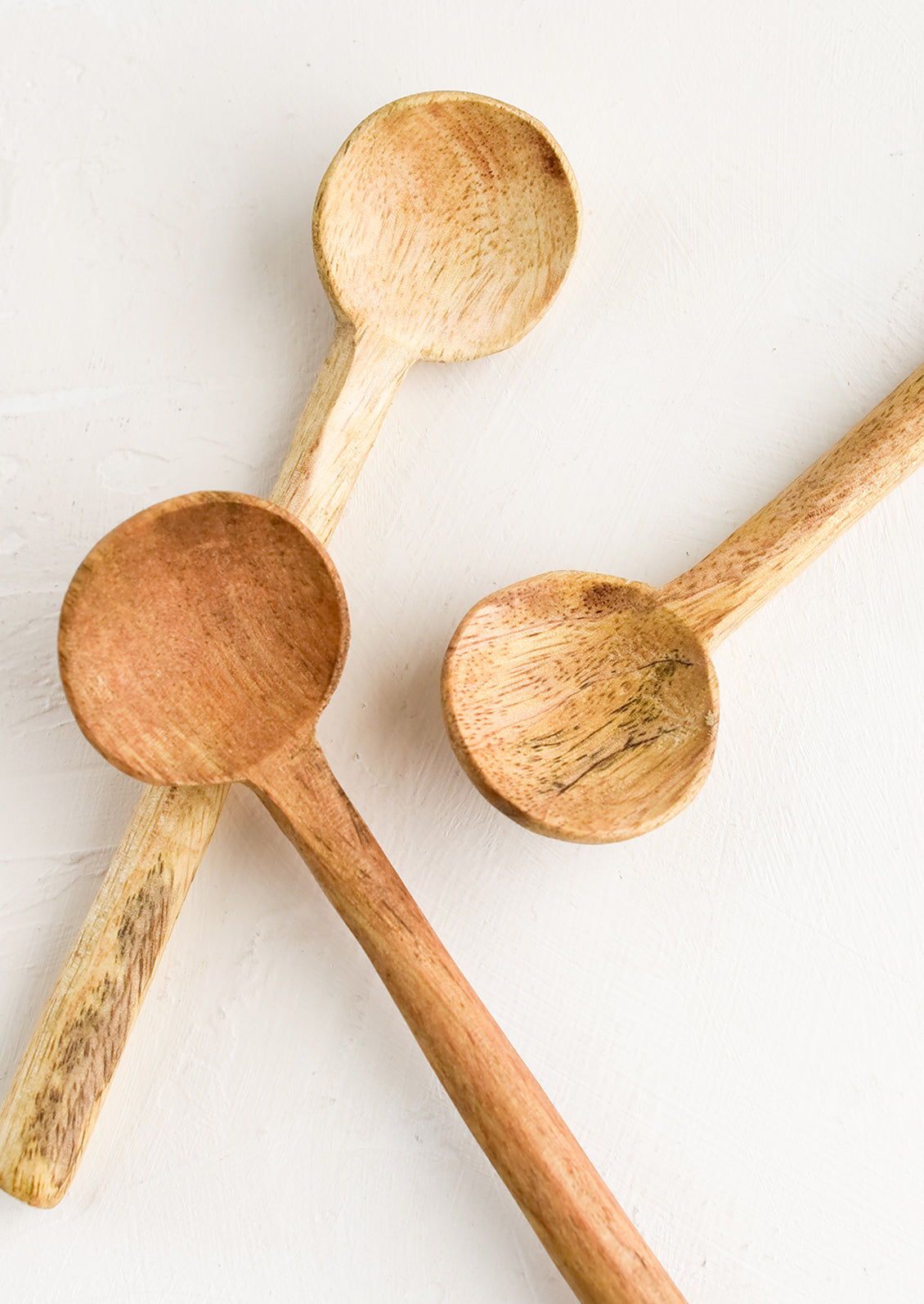 Three carved wooden teaspoons in slightly different wood colors.