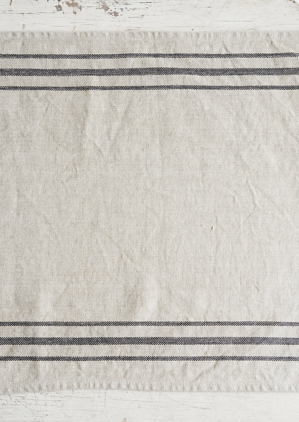 A linen table runner with stripes at sides.