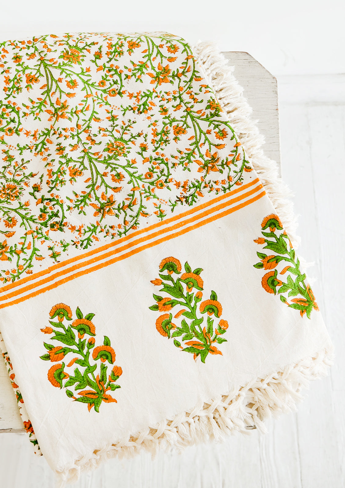 Block printed cotton tablecloth with orange and green floral pattern and tasseled edges