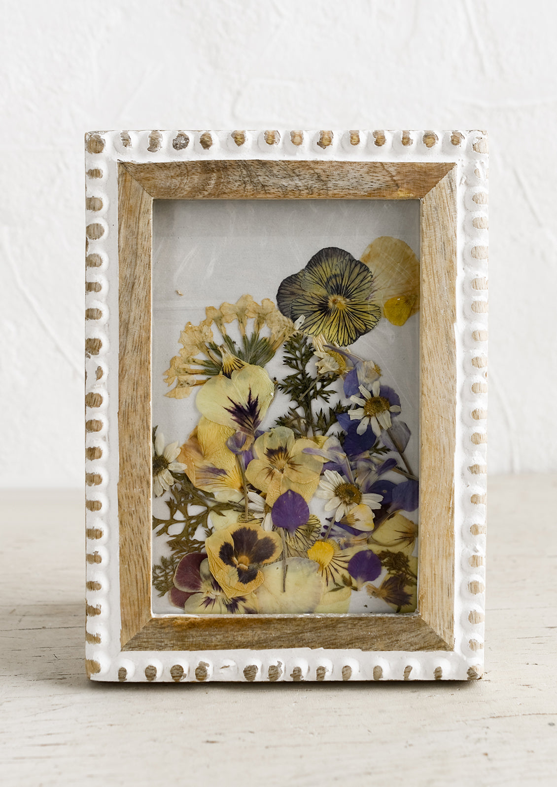A wooden picture frame with whitewash bead textured border.