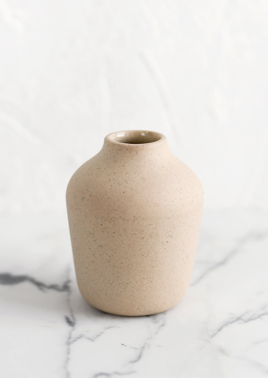 A sand colored porcelain bud vase.