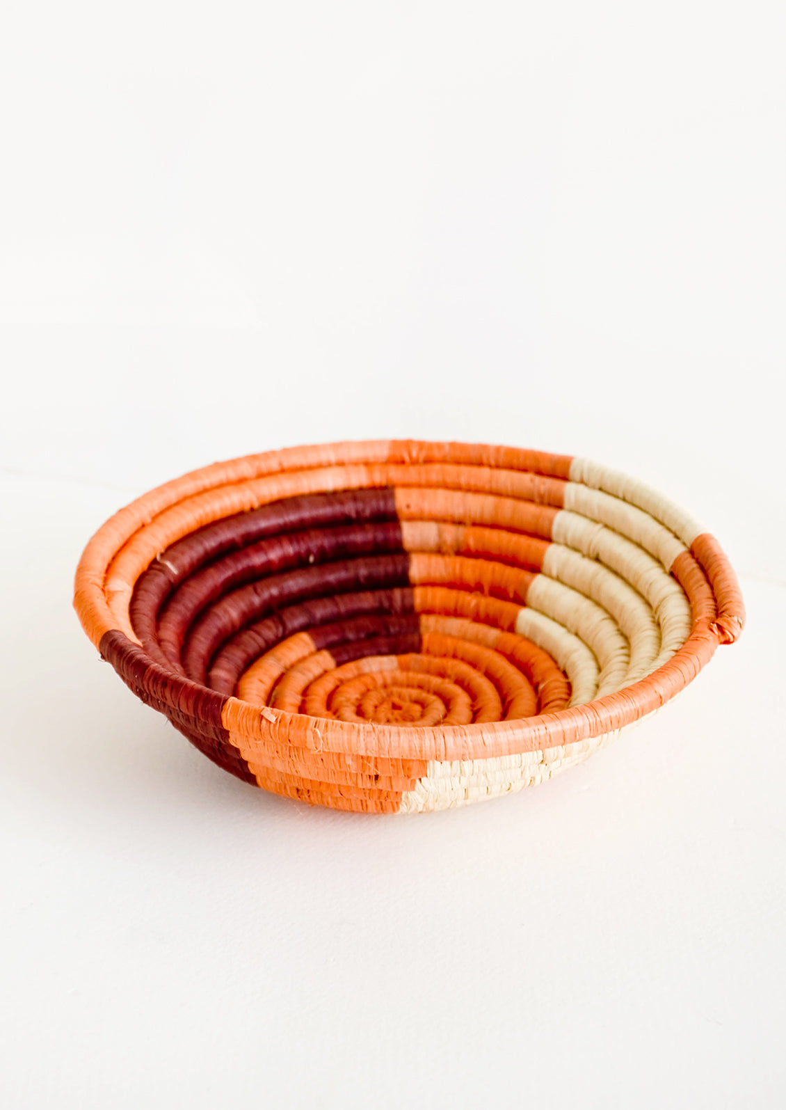 Small raffia bowl in geometric pattern in coral, wine and natural