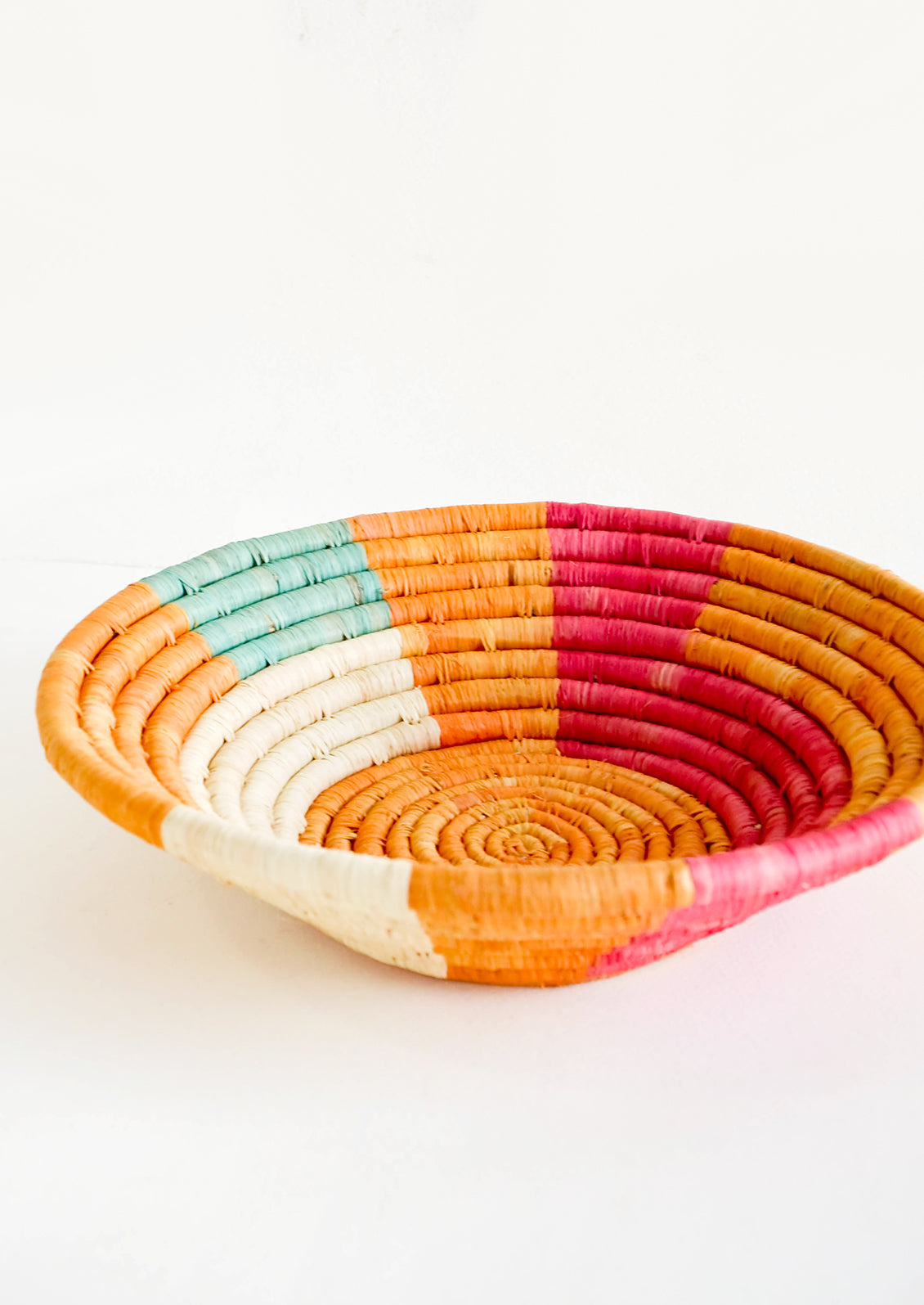 Shallow raffia bowl in mustard, pink, natural and turquoise geometric pattern