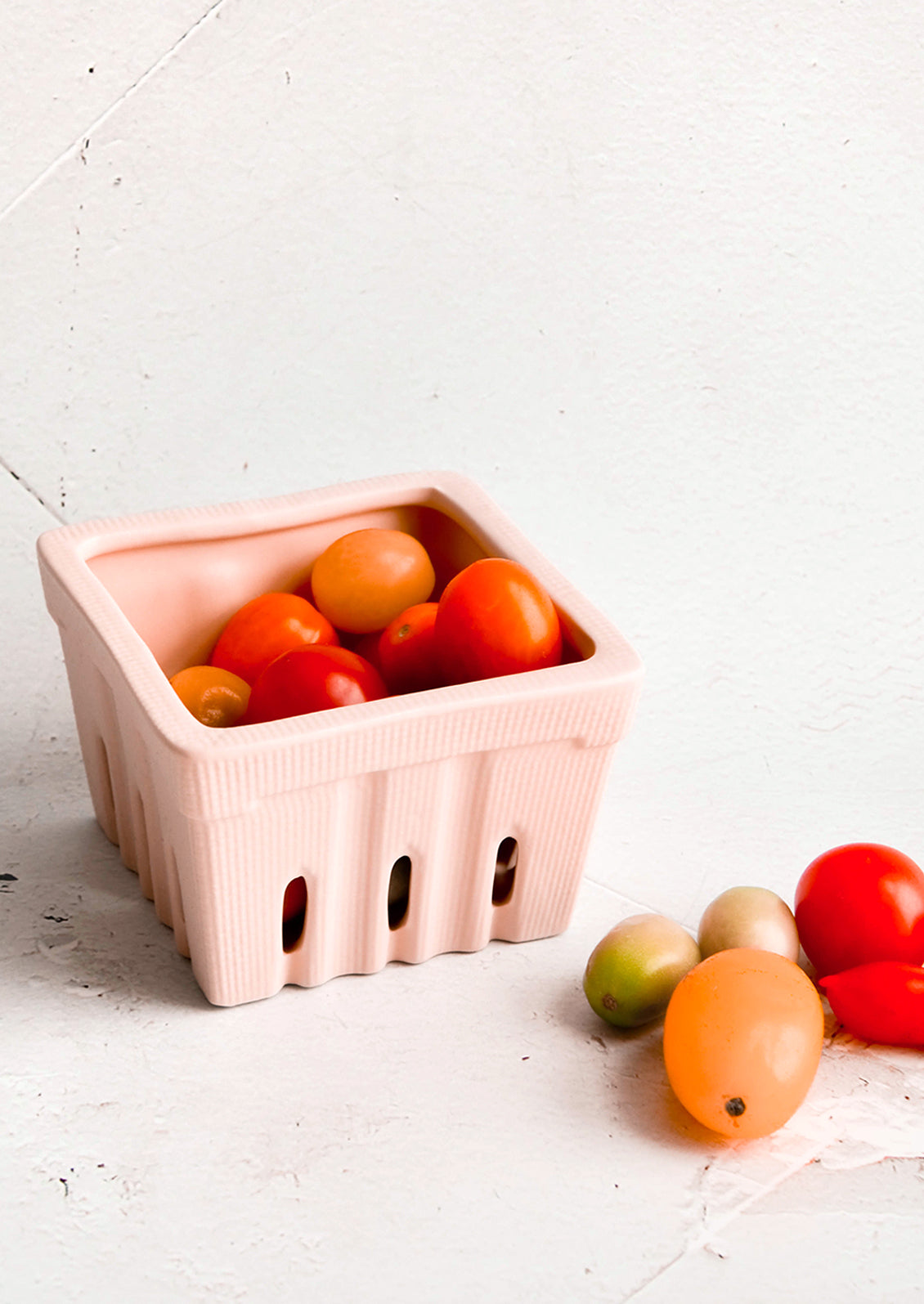 Ceramic basket in the style of disposable berry basket, displayed with cherry tomatoes