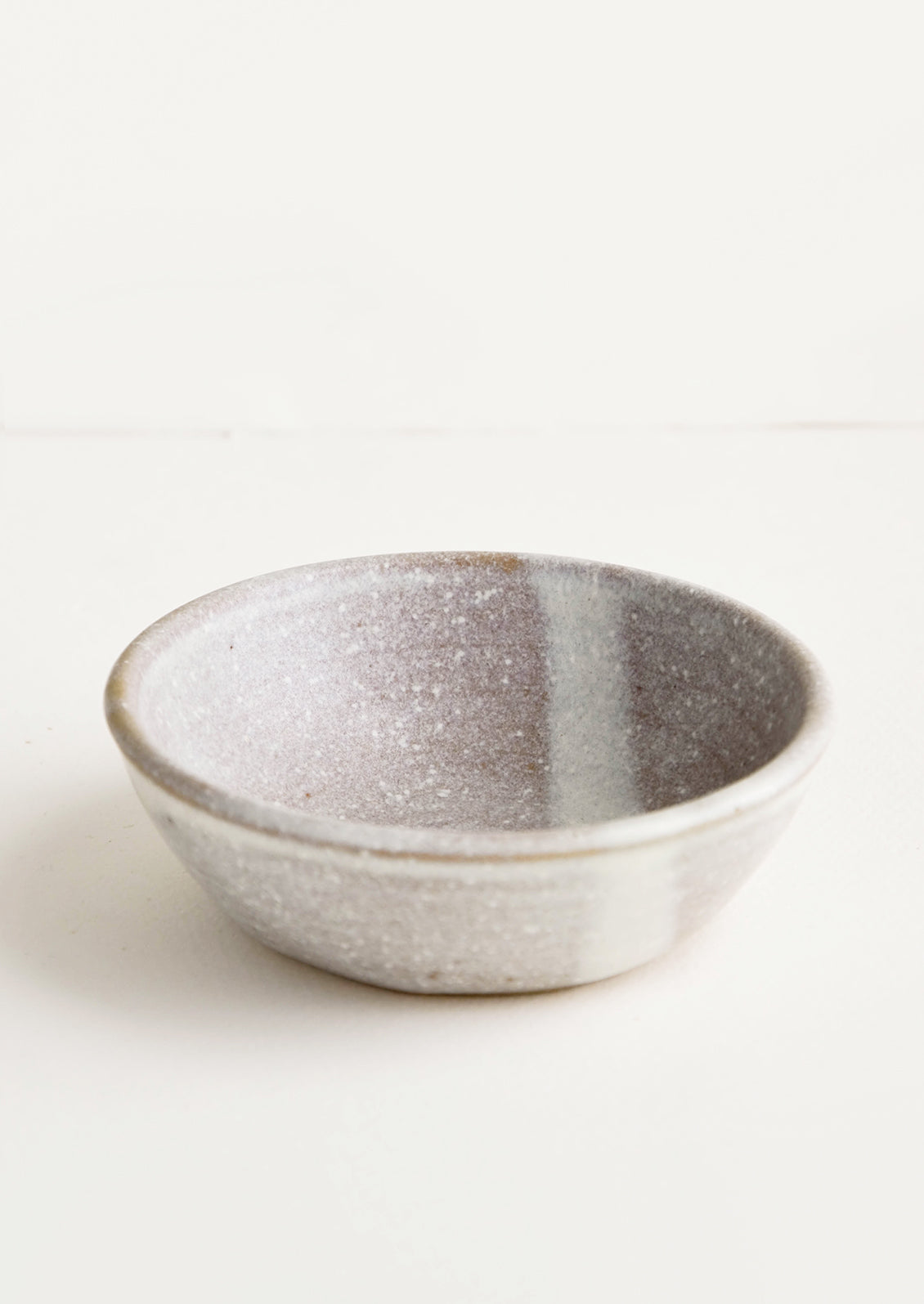 Small, handmade ceramic pinch bowl in speckled light brown and white glaze