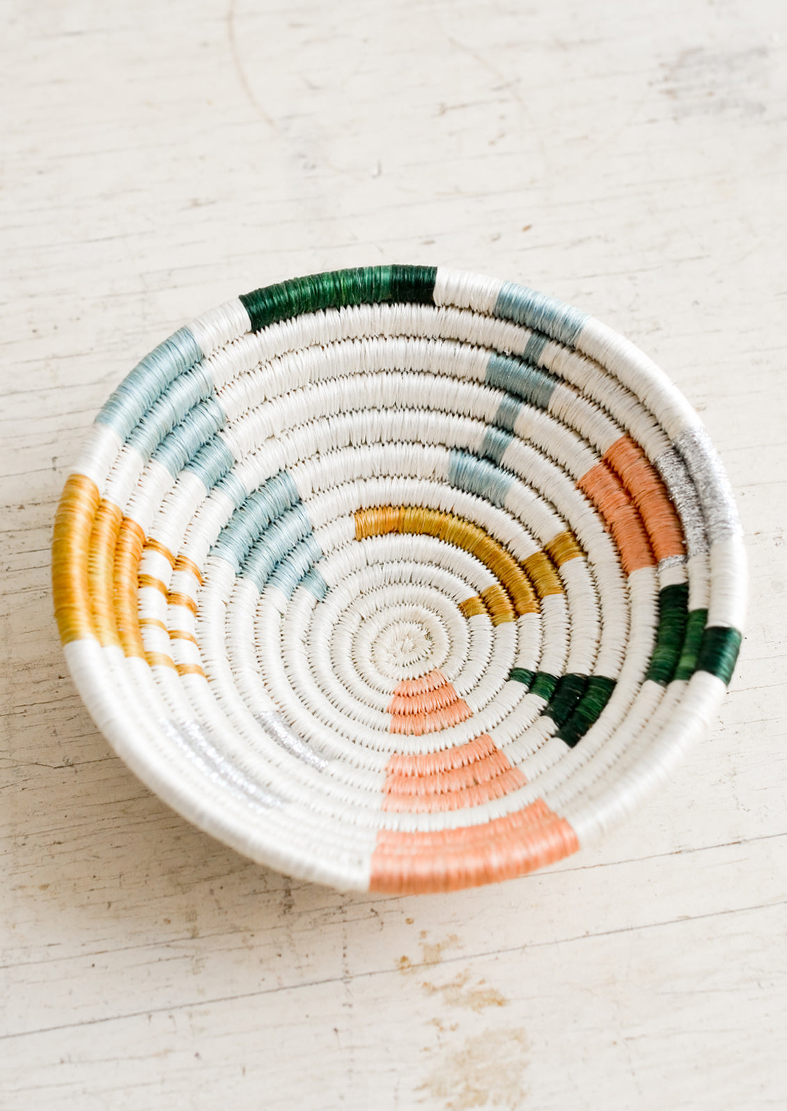A small catchall bowl made from sweetgrass in pastel colored geometric pattern.