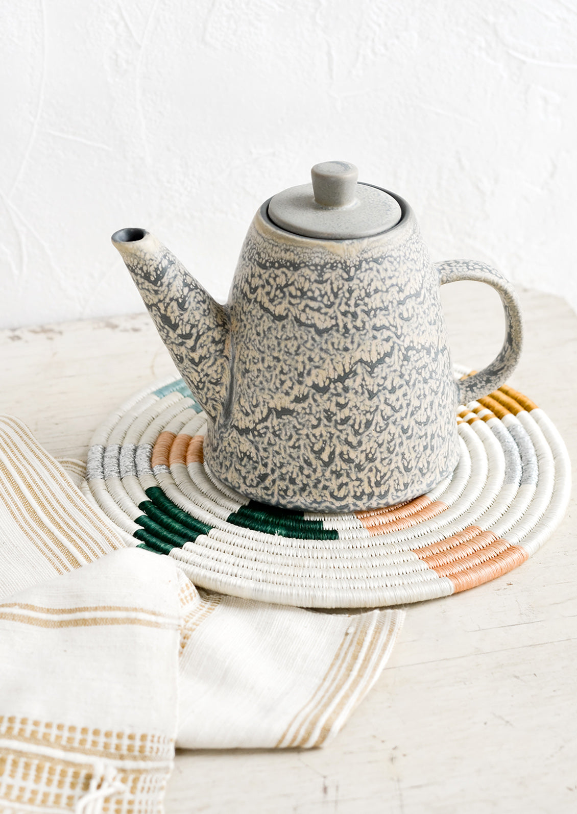 A grey ceramic teapot on table.