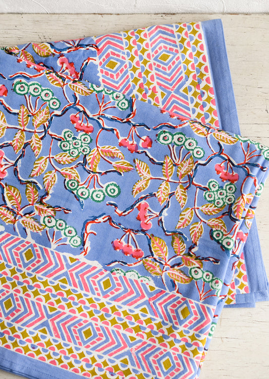 A block printed table cloth in yellow, blue and pink floral print with geometric border.