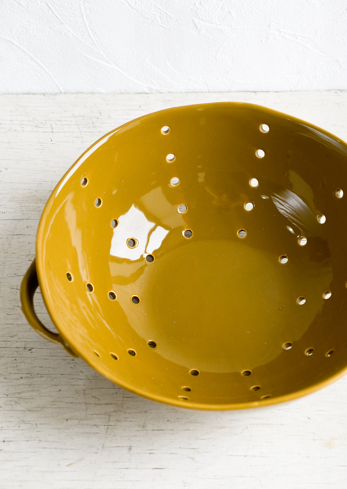 A large ceramic colander with side handles.