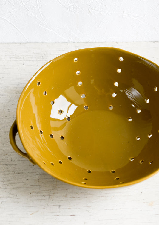 A large ceramic colander with side handles.