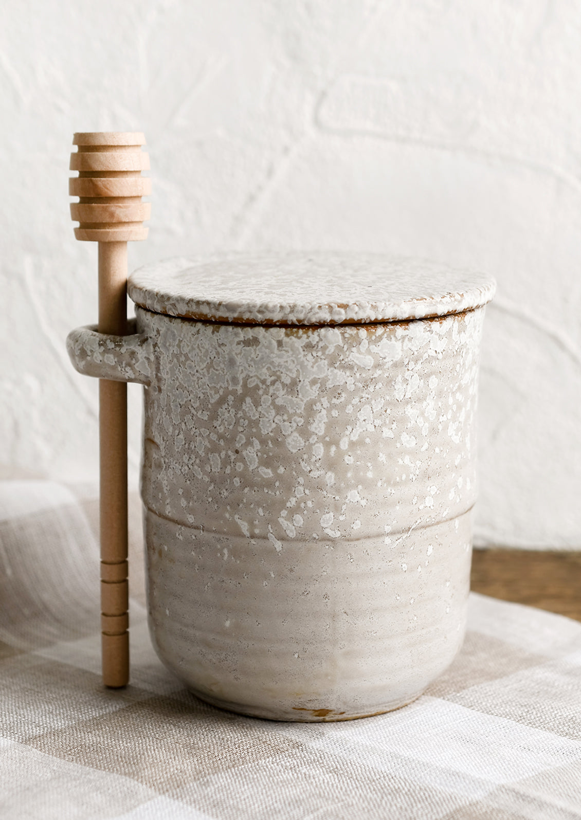 A ceramic honey jar in grey ceramic with white speckles.