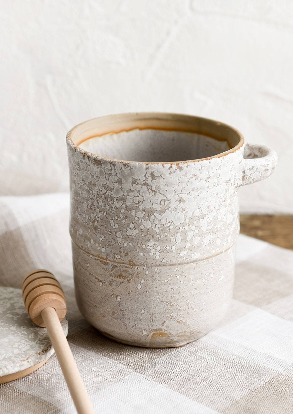 A ceramic honey jar in grey ceramic with white speckles.