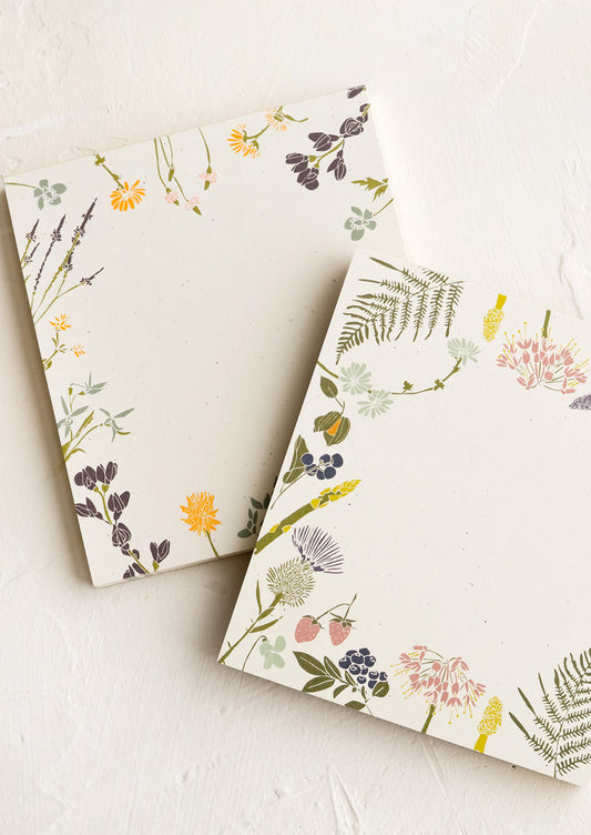 Two square notepads with botanical borders in different designs.