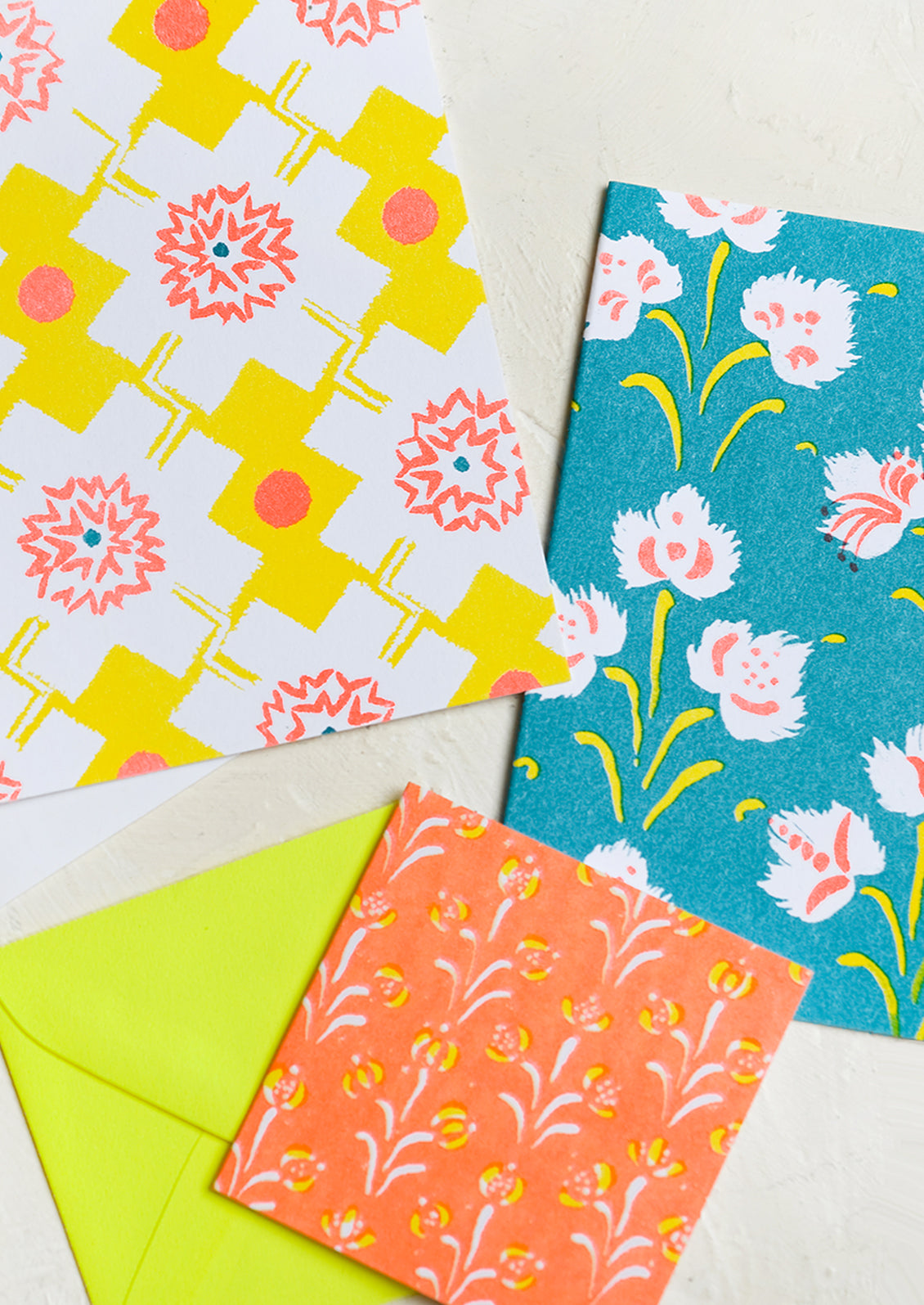 A patterned risograph printed card set in yellow, teal and orange.
