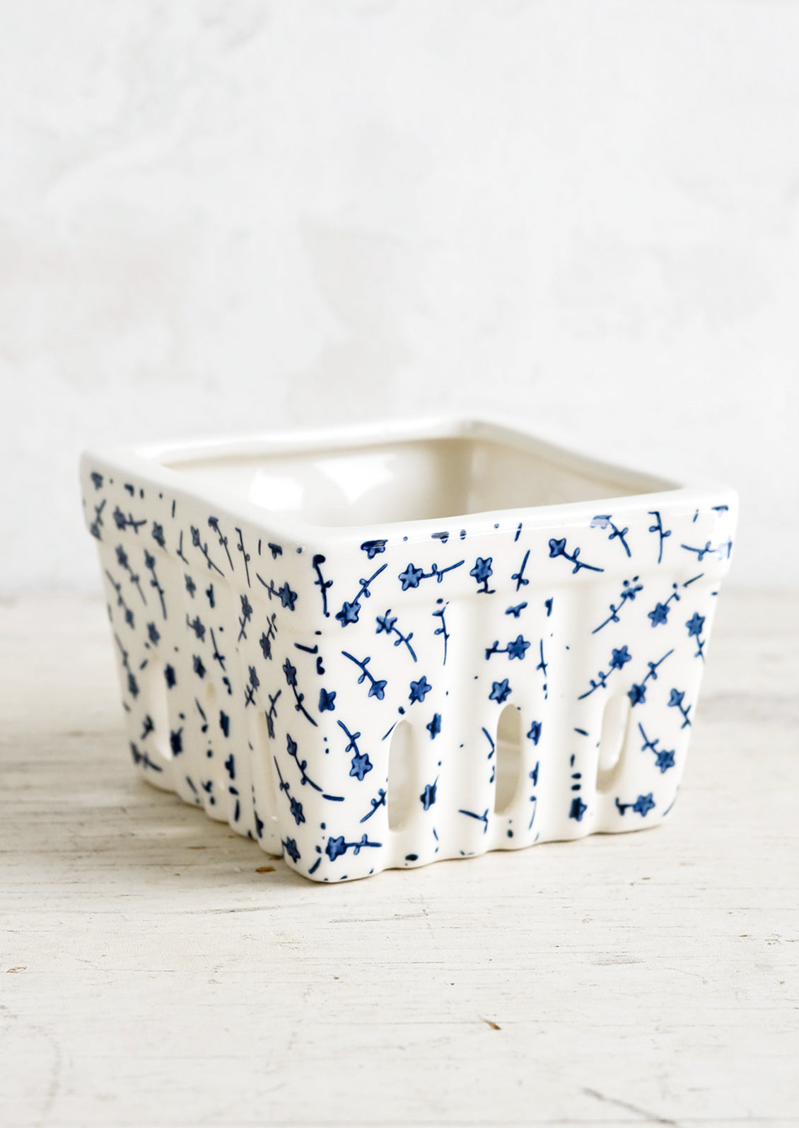A ceramic berry basket  with blue ditsy floral print on white ceramic.