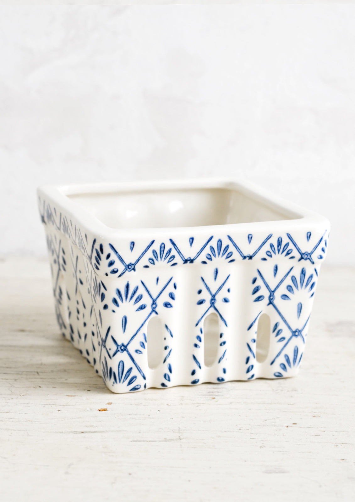 A ceramic berry basket with blue tilework print on white ceramic.