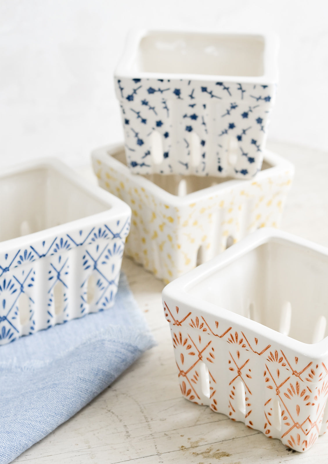 White ceramic berry baskets in primary colors and assorted patterns.