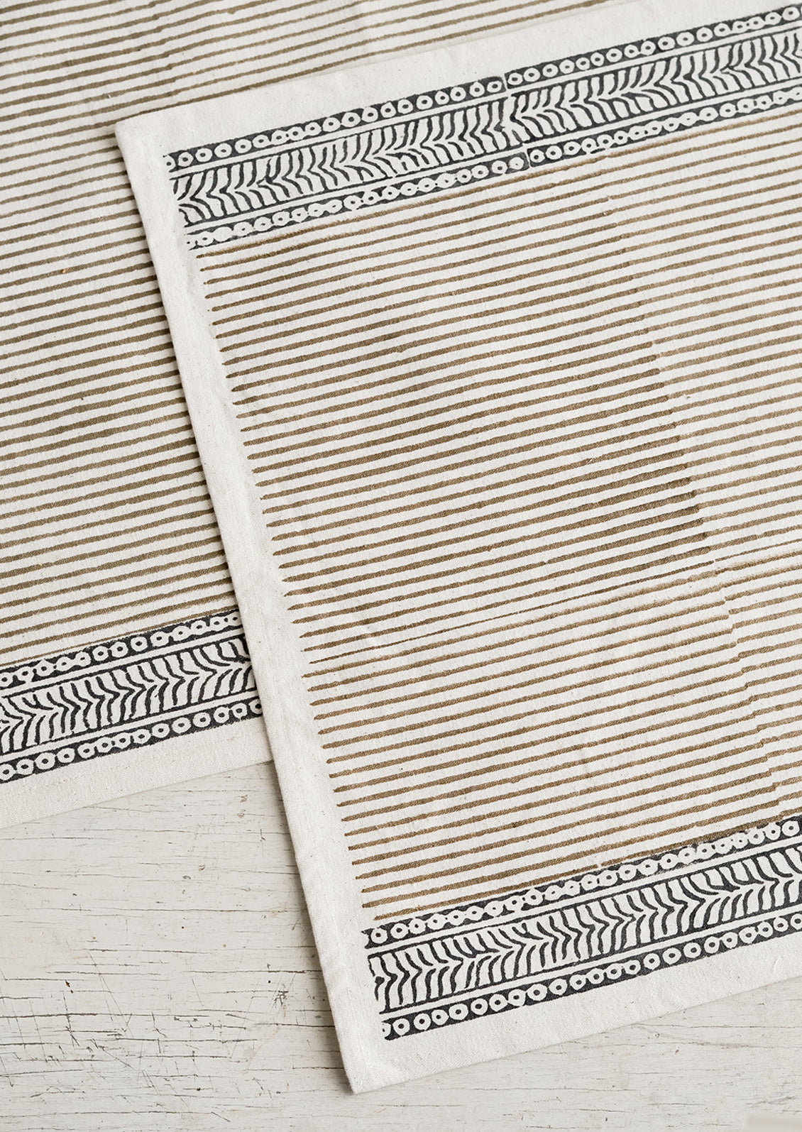 A cotton placemat with block print design, borders at top and bottom with striped center.