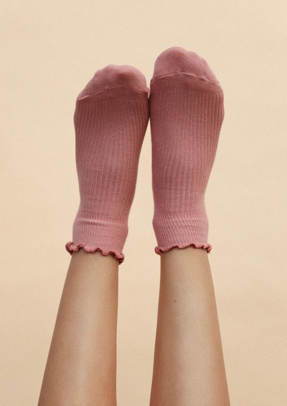 Legs wearing a pair of pink ankle socks.