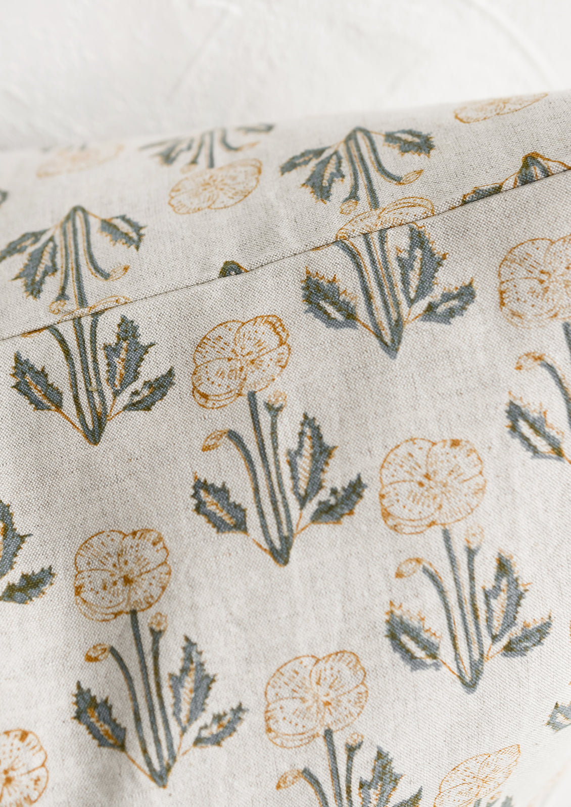 A natural linen throw pillow with floral block print pattern.