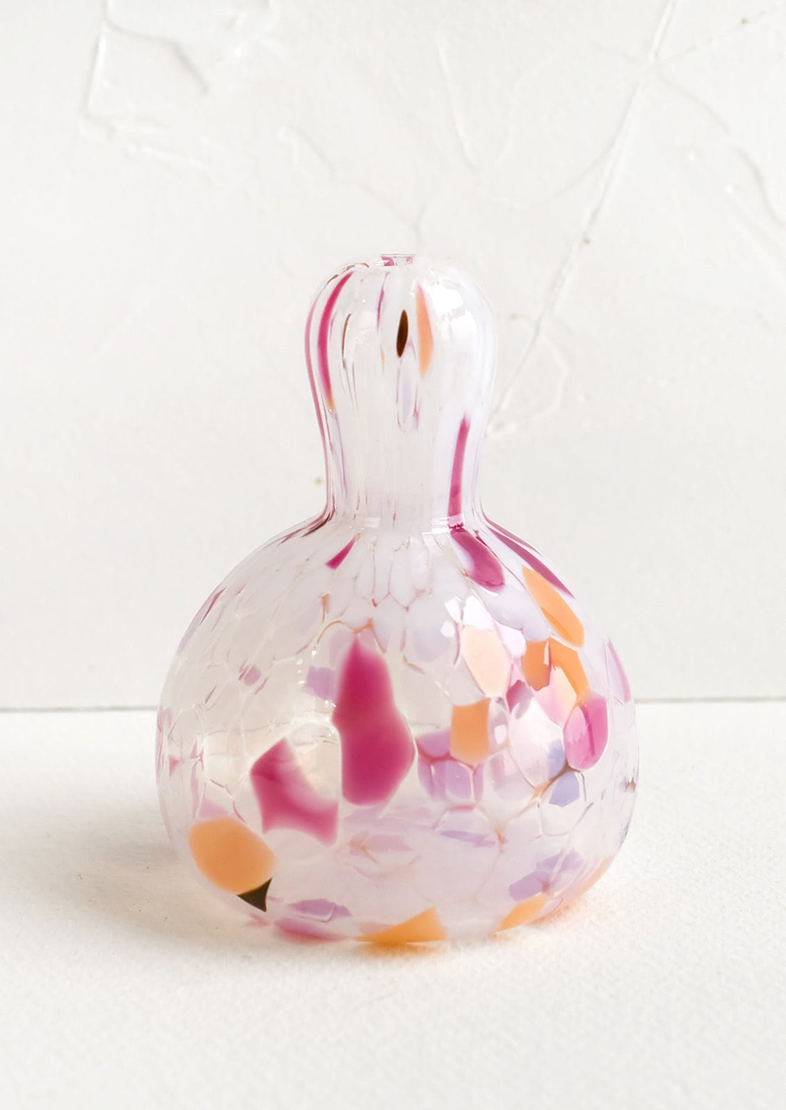 A gourd shaped bud vase in glass with orange, brown and pink speckles.