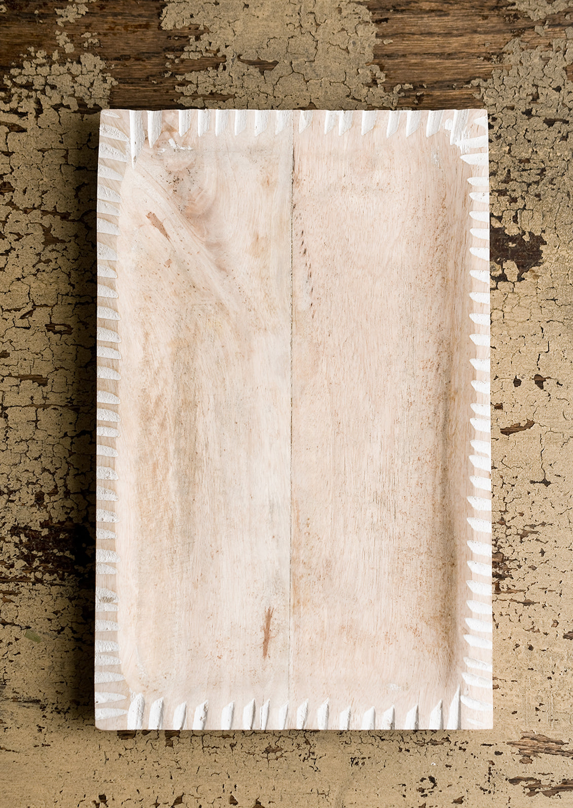 A rectangular tray in light colored wood with white painted notched border.