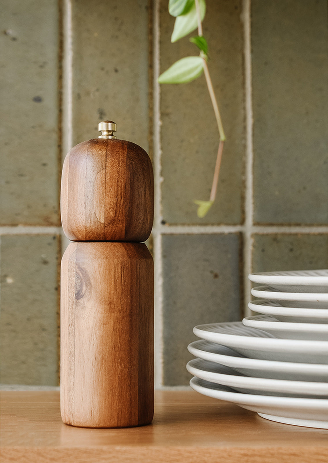 A wooden pepper grinder on a kitchen shelf.