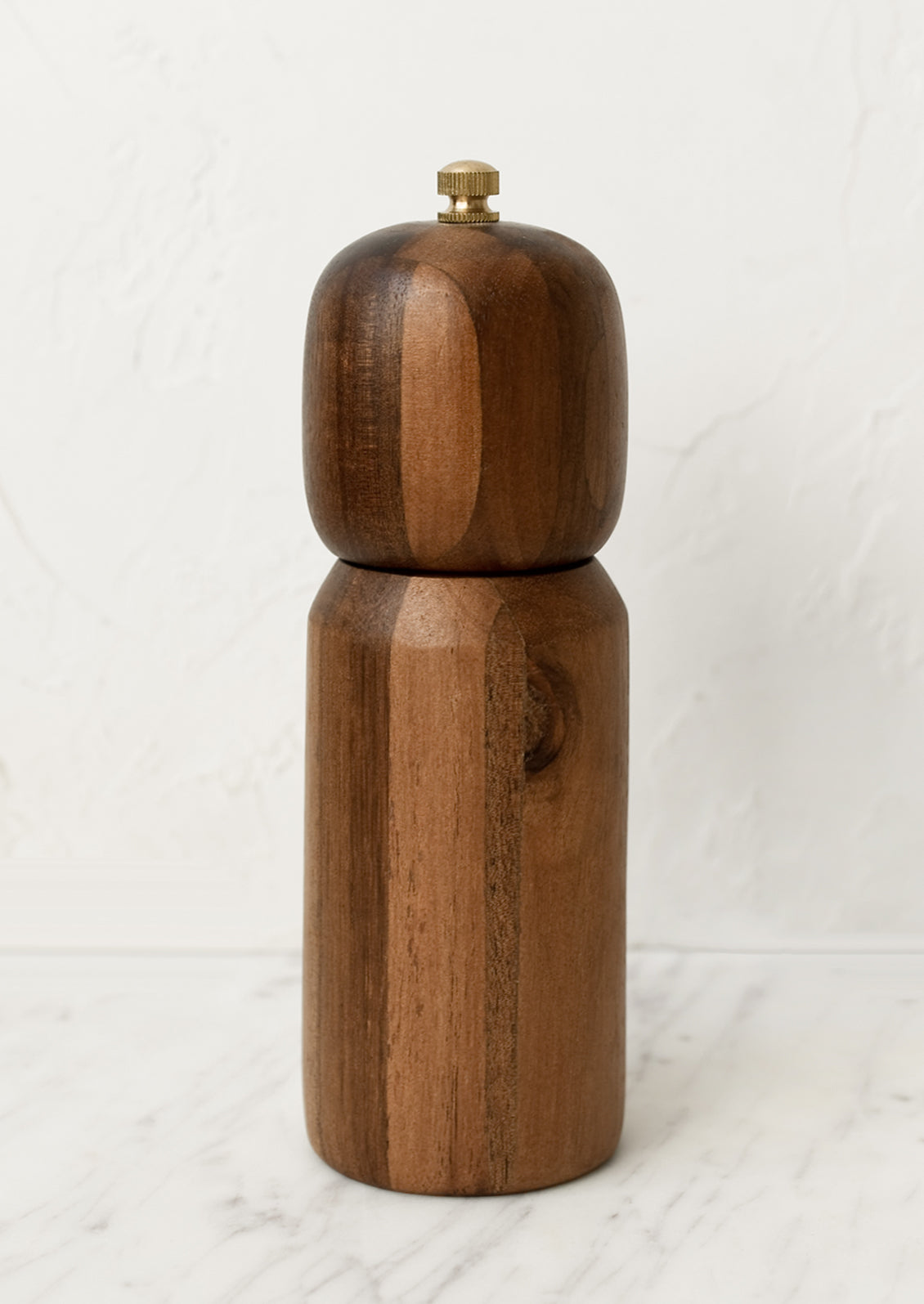 A wooden pepper mill with rounded shape and brass tip.
