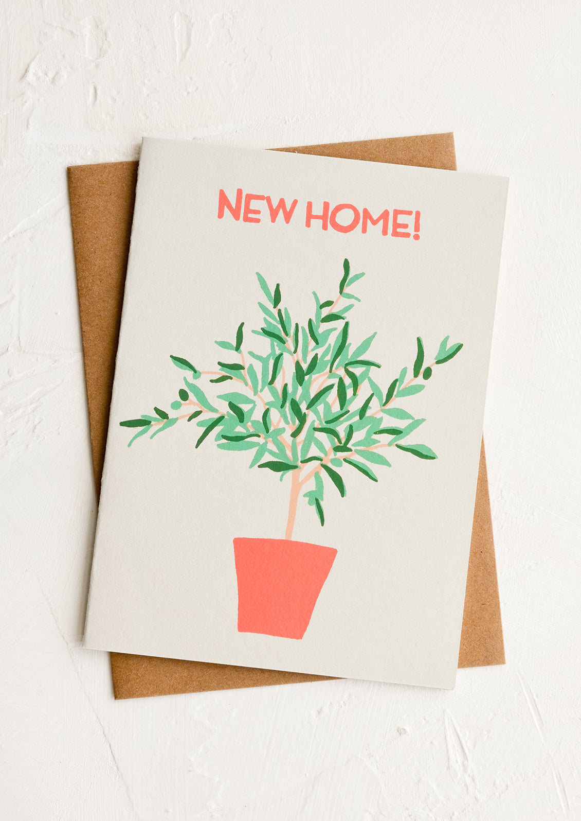 A greeting card with screen printed olive tree and "NEW HOME!" in red lettering.