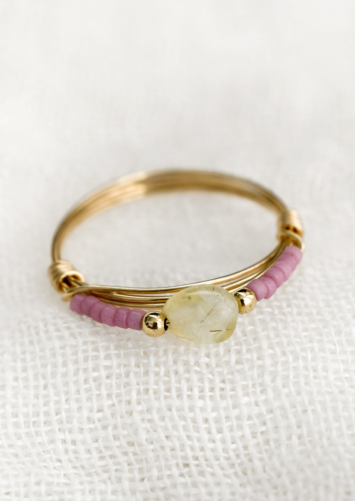 A gold wire ring with mauve and gemstone beads.