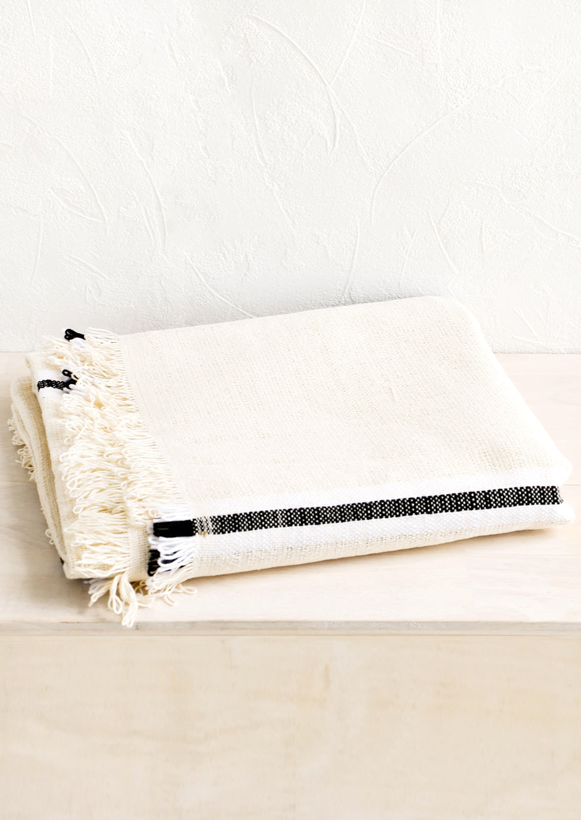 Folded cotton blanket in natural color with black and white stripe