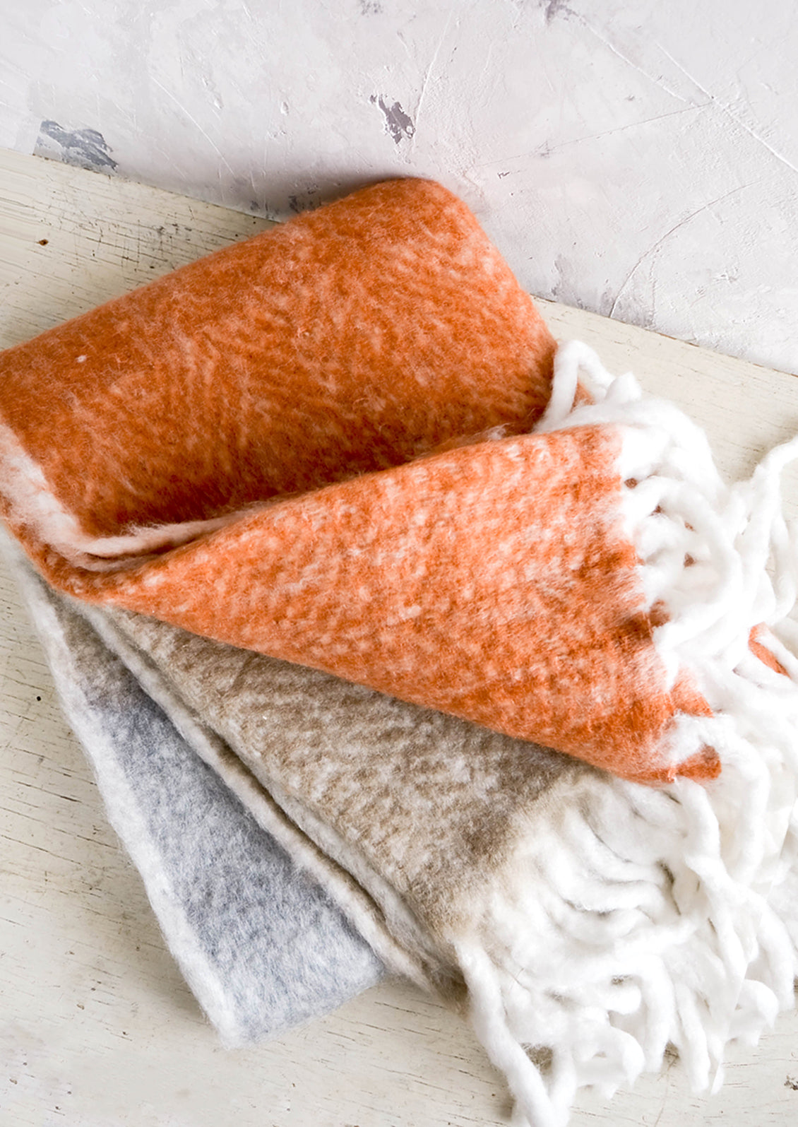 Chunky knit throw blanket in tricolor design with chunky white fringe trim