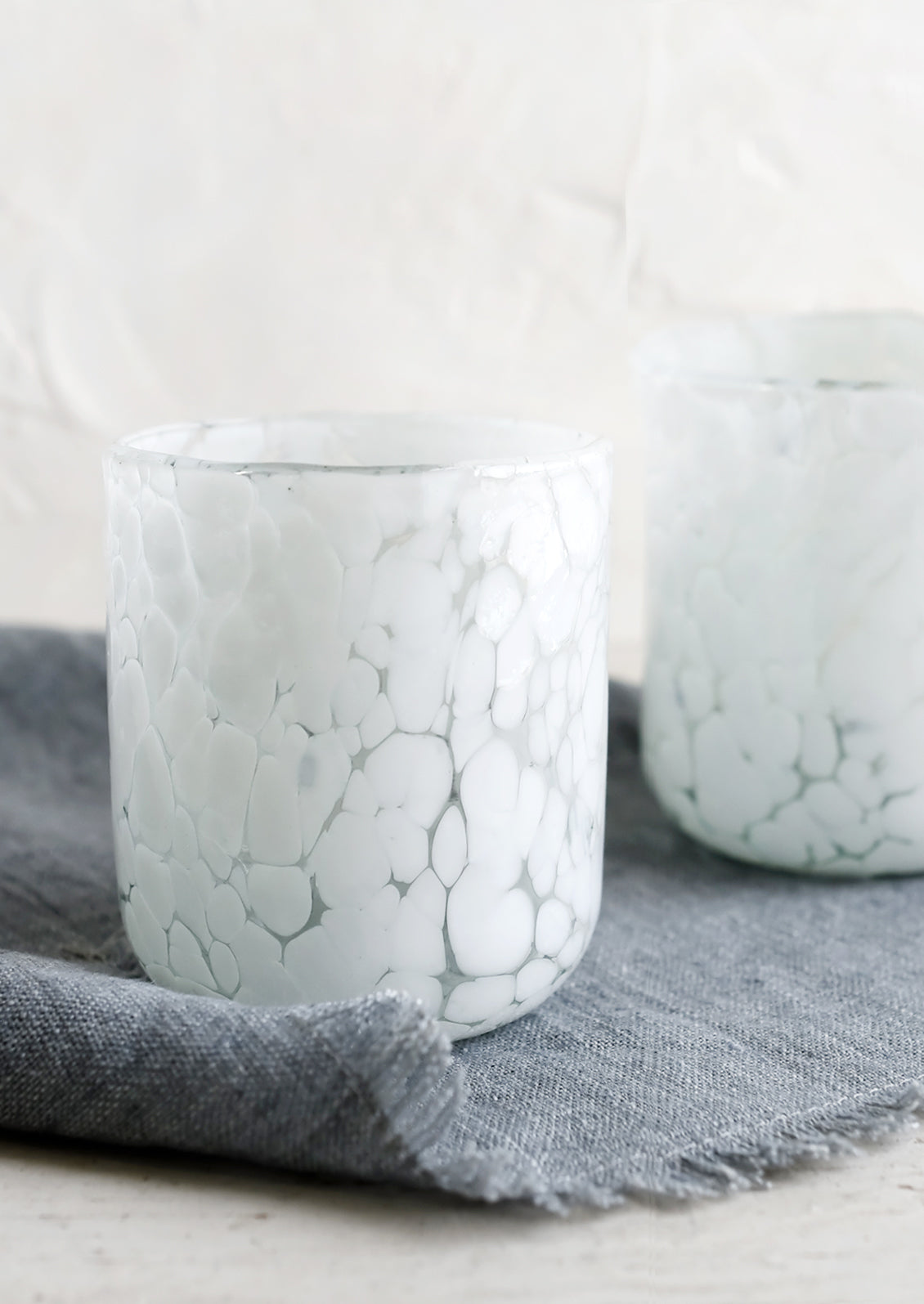 A pair of white speckled tumbler rocks glasses.