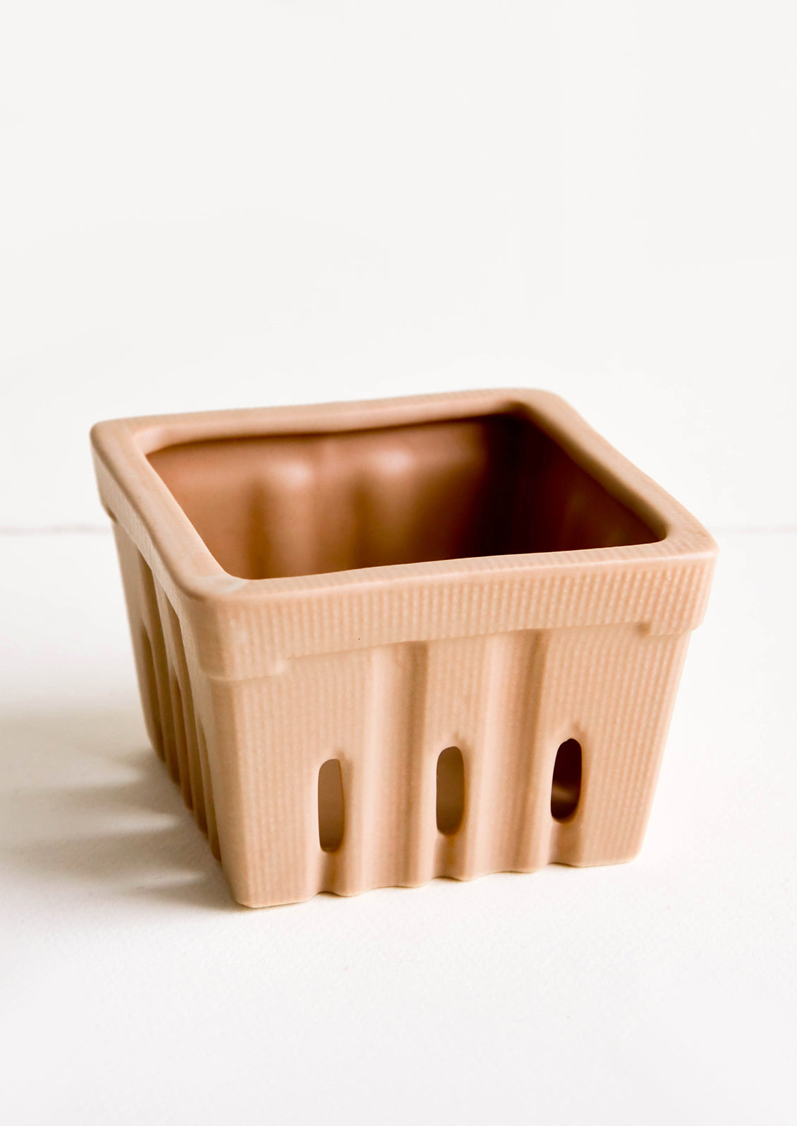 Ceramic basket in the style of disposable berry basket, shown in cocoa brown