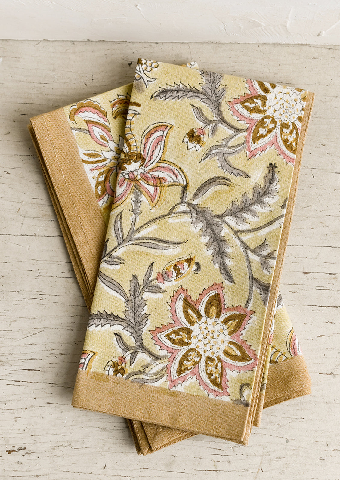 A pair of yellow floral paisley print napkins.