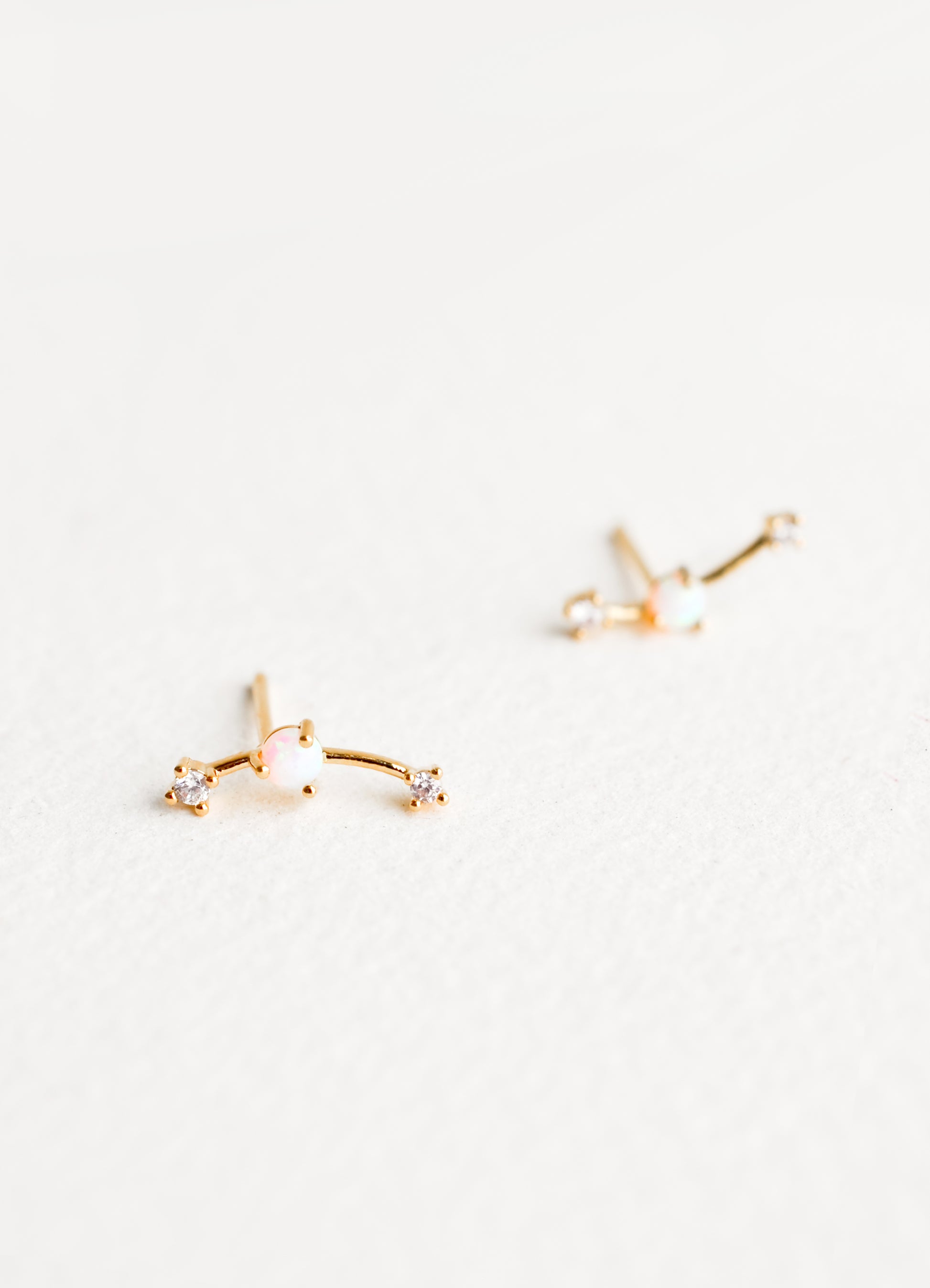 Climber style stud earrings with opal center and rhinestones at ends.