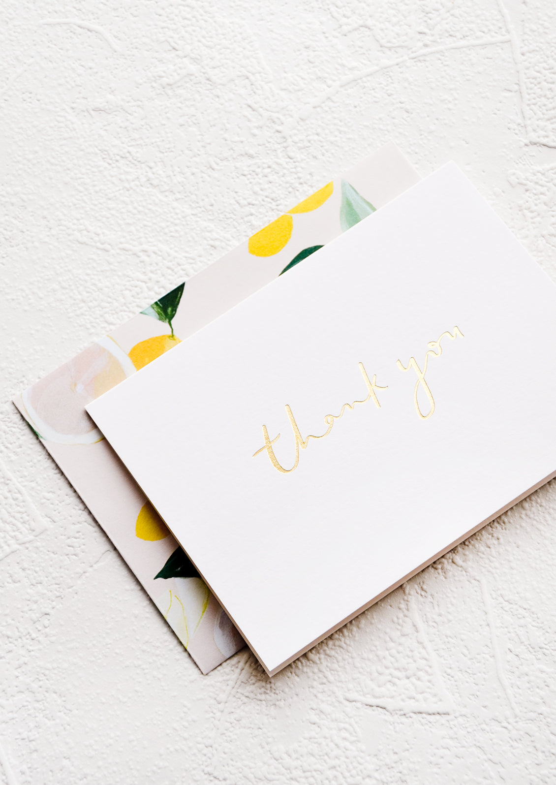 White greeting card with "Thank you" in gold script and citrus patterned envelope