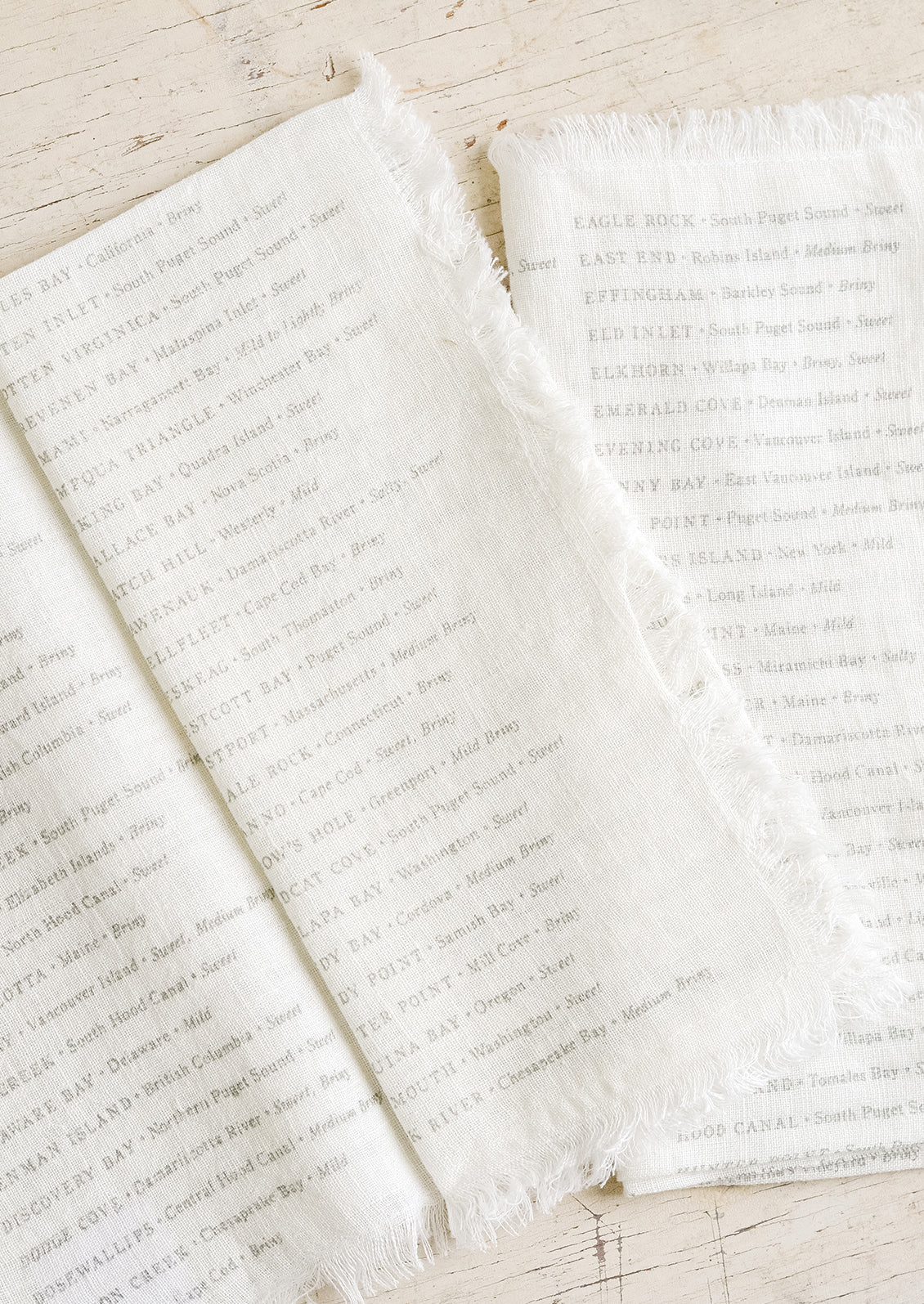 White linen napkins with grey text listing out oyster types and their origins.